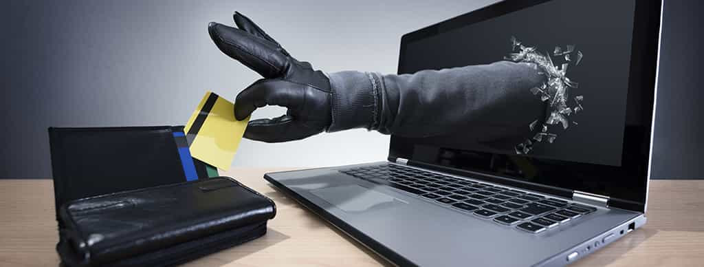 En hånd gennem computerskærmen, der stjæler et kort fra en pung.