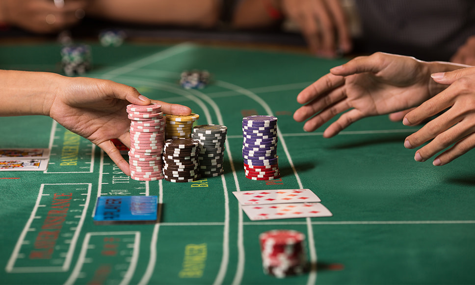 En dealer vender kort på et baccaratbord med fokus på chips og indsatsfelter. 