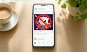 Telefon på et træbord, hvor en casino-annonce i et socialt feed er blokeret med et rødt forbudsskilt